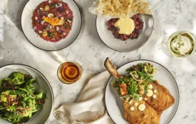 A marble table spread with gourmet Italian dishes including veal milanese and beef tartare at Ristorante Per L'Ora.