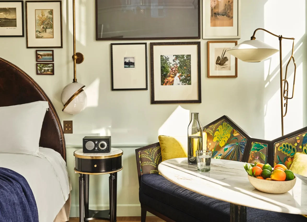Sunlight streams into a luxury hotel suite in Los Angeles featuring an artistic gallery wall and cozy dining nook.