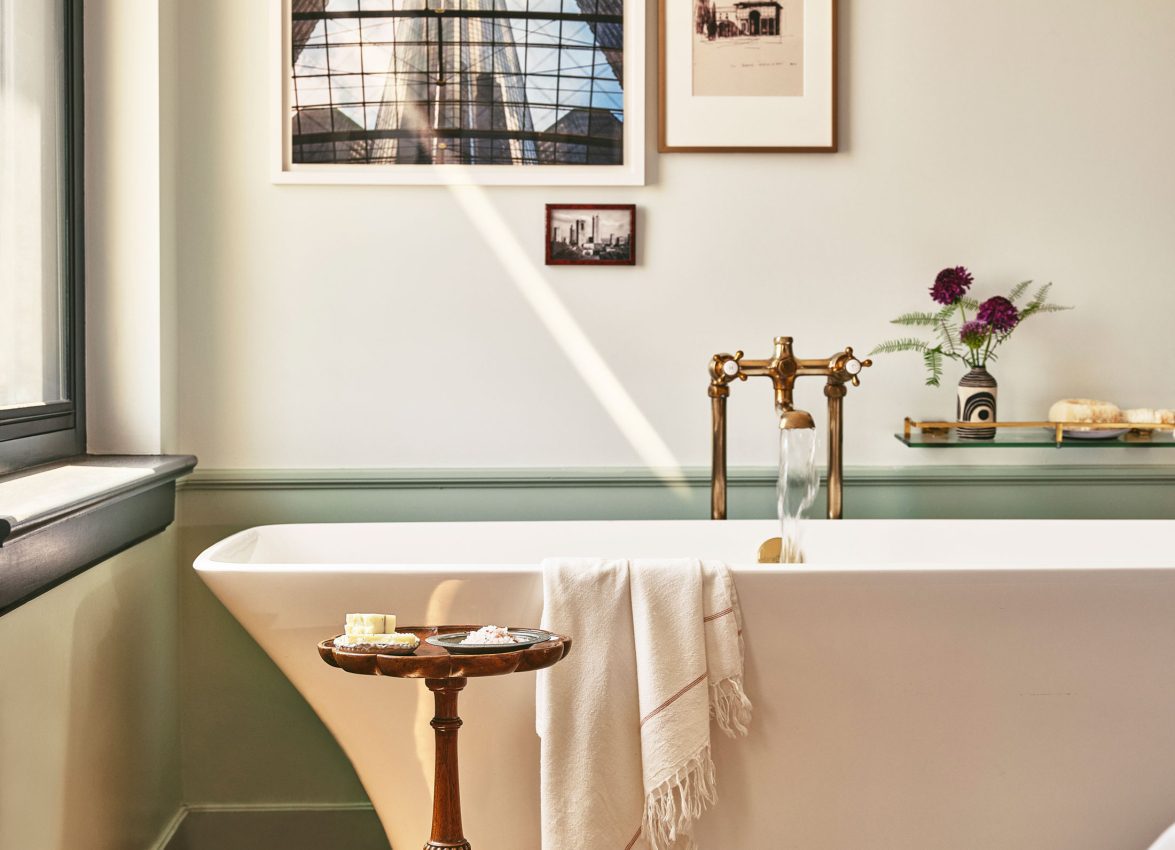 Sunlight illuminates a white soaking tub and vintage-style brass fixtures in a refined suite at Hotel Per La.