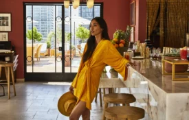 A woman in a yellow dress leans against the marble counter at Bar Clara, a stylish rooftop bar in Los Angeles.