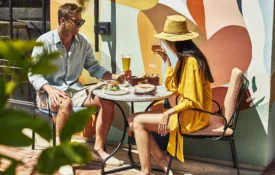 A couple enjoys drinks and appetizers at Bar Clara, a vibrant rooftop bar in Los Angeles with colorful wall murals.