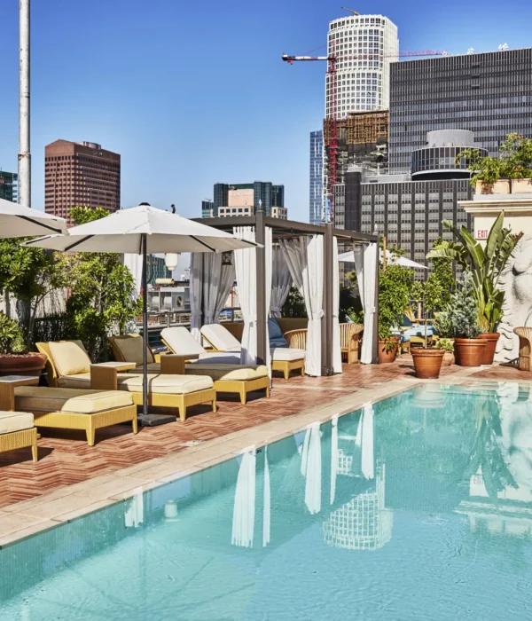 Guests enjoy the Bar Clara rooftop pool hotel Los Angeles deck featuring plush loungers and a carved stone facade.