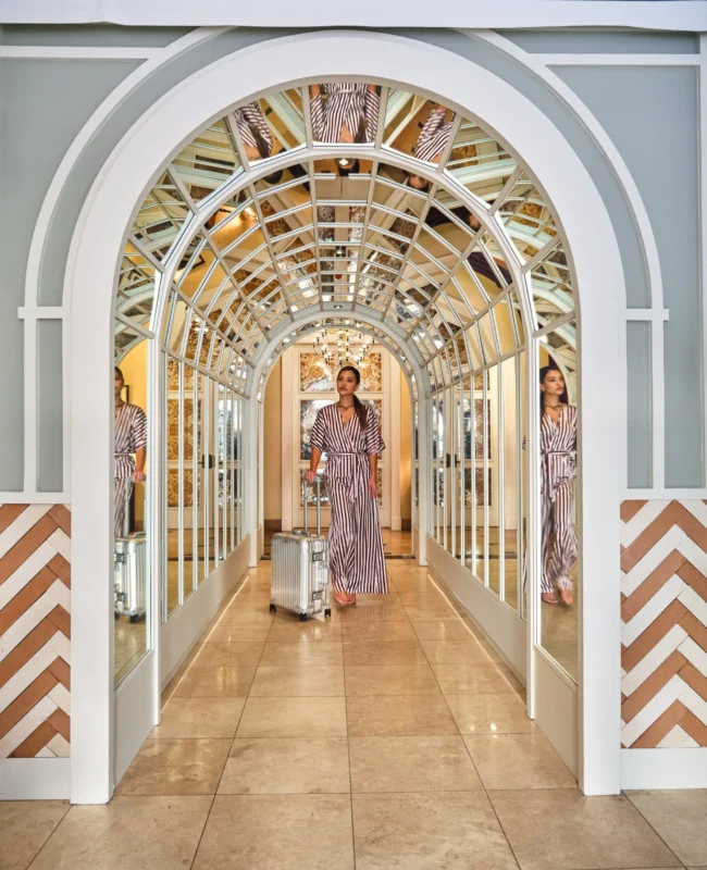 A woman pulls a suitcase through a glamorous mirrored archway at Hotel Per La in downtown Los Angeles.