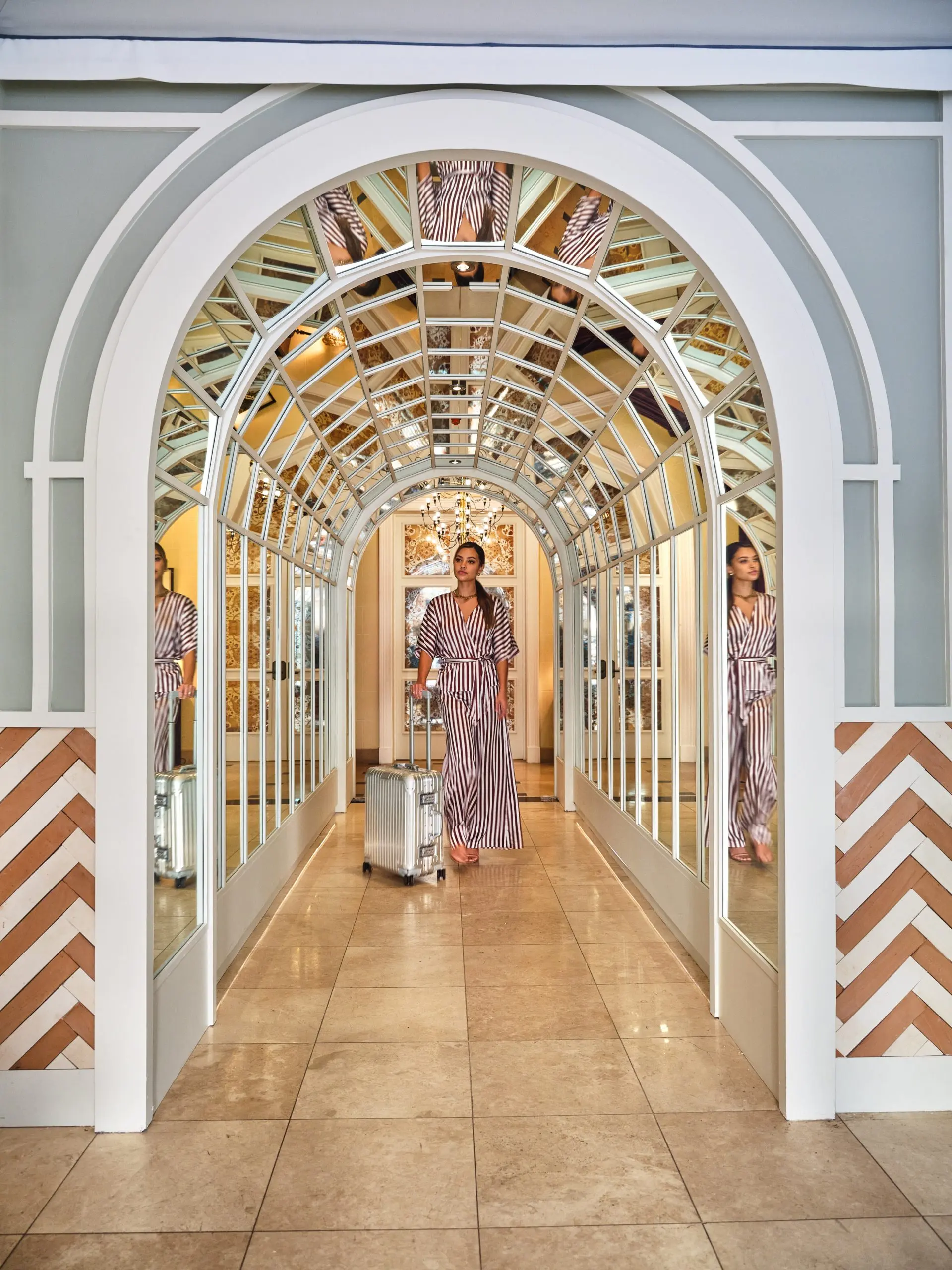 A woman pulls a suitcase through a glamorous mirrored archway at Hotel Per La in downtown Los Angeles.