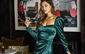 A woman in a green satin dress holds a cocktail in the stylish Bar Clara at our boutique hotel in downtown LA.