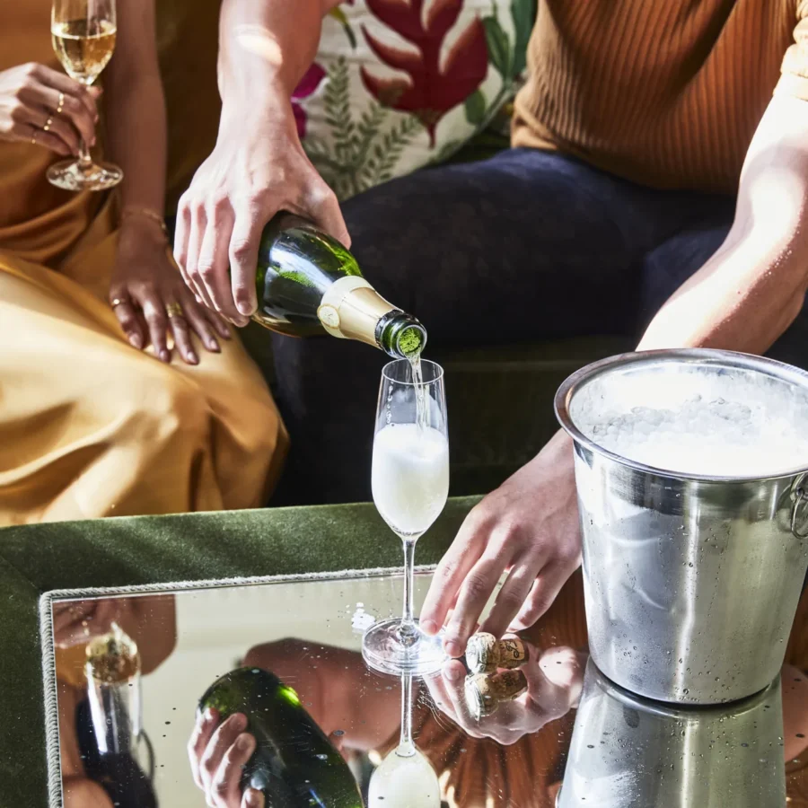 A man pours sparkling champagne into a flute for a guest in a luxurious Hotel Per La suite.