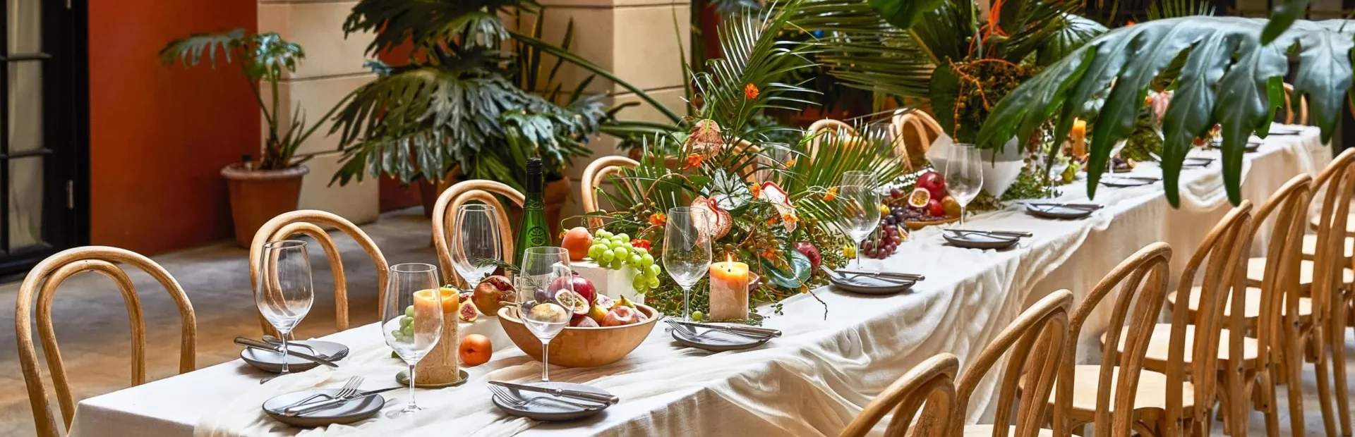 Lush tropical centerpieces and fresh fruit adorn a long banquet table at this boutique Los Angeles event venue.