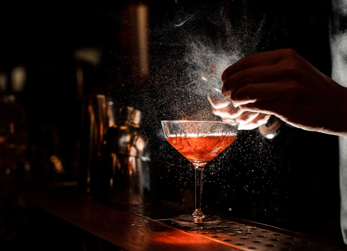 A bartender finishes a red cocktail with a fine mist at Bar Clara, a top rooftop bar in Los Angeles.