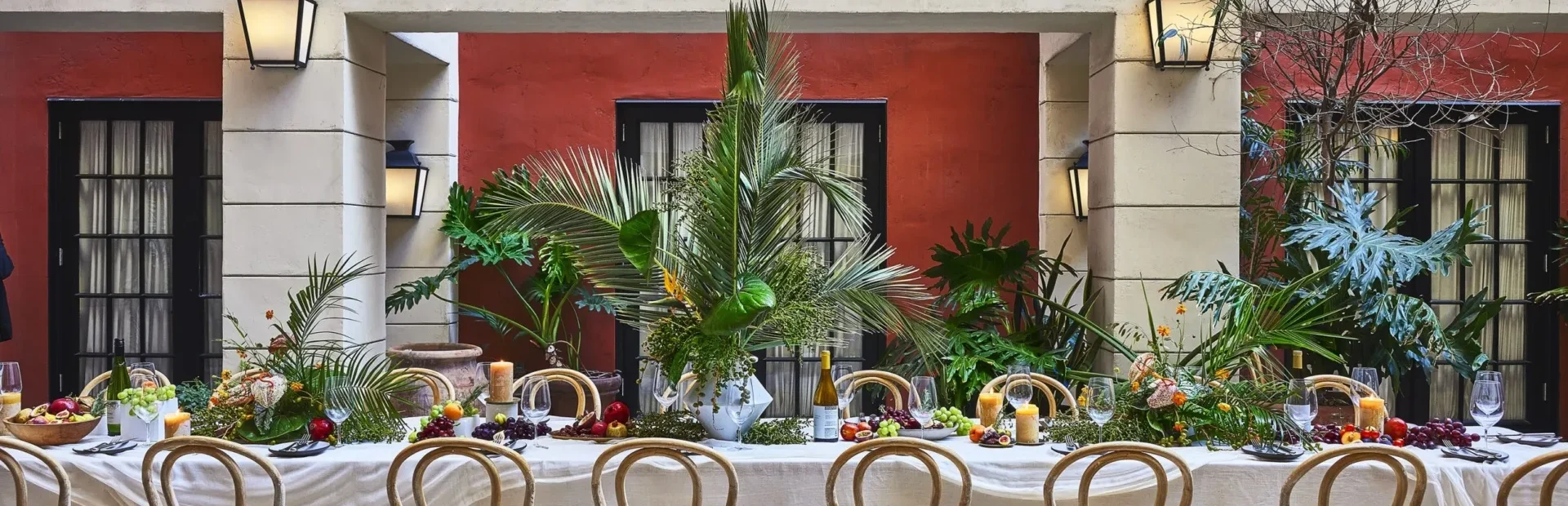A long banquet table with tropical greenery and wine for a gathering at our hotel event spaces in LA.