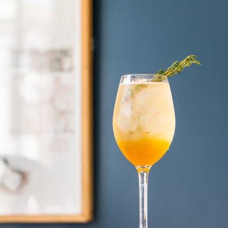 A vibrant citrus cocktail with a fresh thyme garnish at Bar Clara, a stylish rooftop bar in downtown Los Angeles.