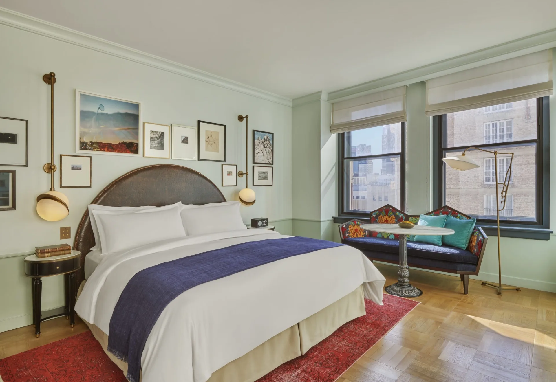 A sophisticated guest room at Hotel Per La with a gallery wall, plush king bed, and sunlit window seating.
