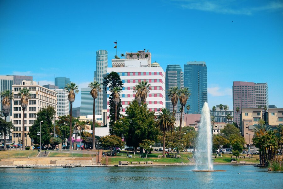 A scenic park with a large fountain and palm trees set against the towering skyscrapers of downtown Los Angeles.