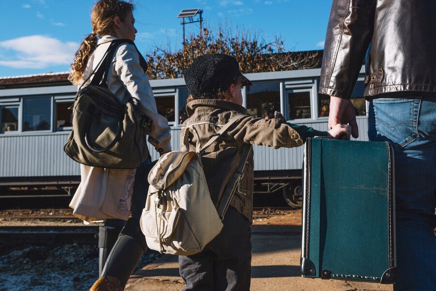 A family carrying suitcases and backpacks walks toward a train carriage while exploring places to stay in Los Angeles.