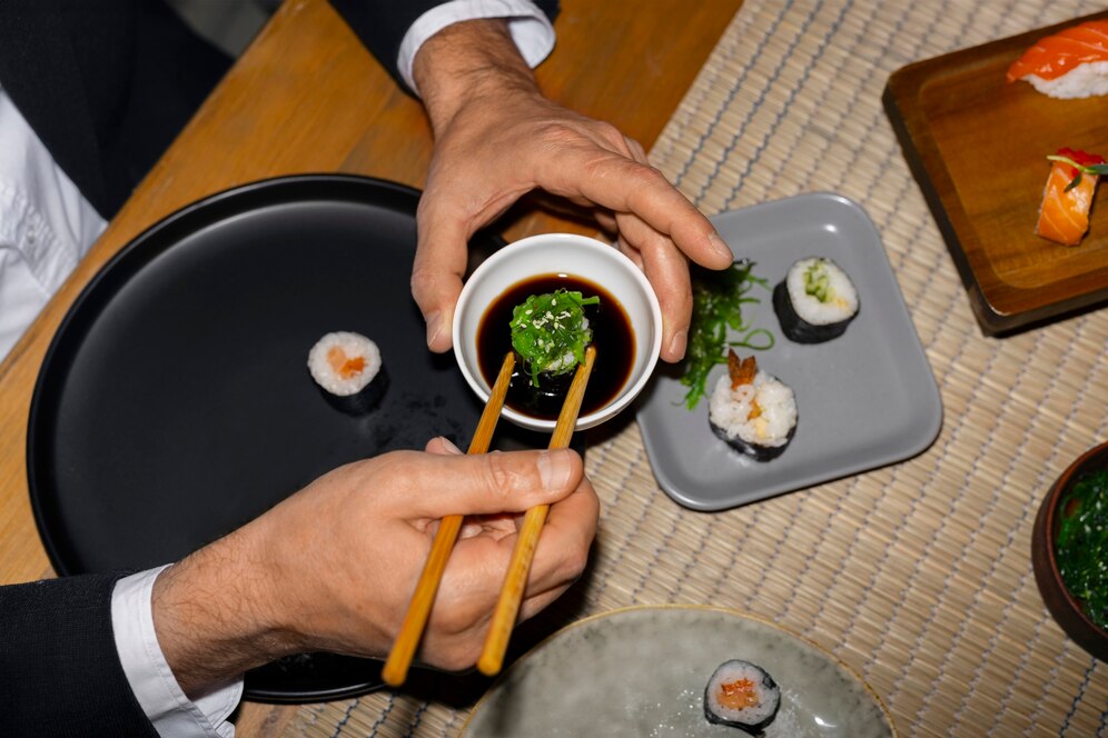 A guest uses chopsticks to dip a sushi roll into soy sauce at one of the downtown LA restaurants.