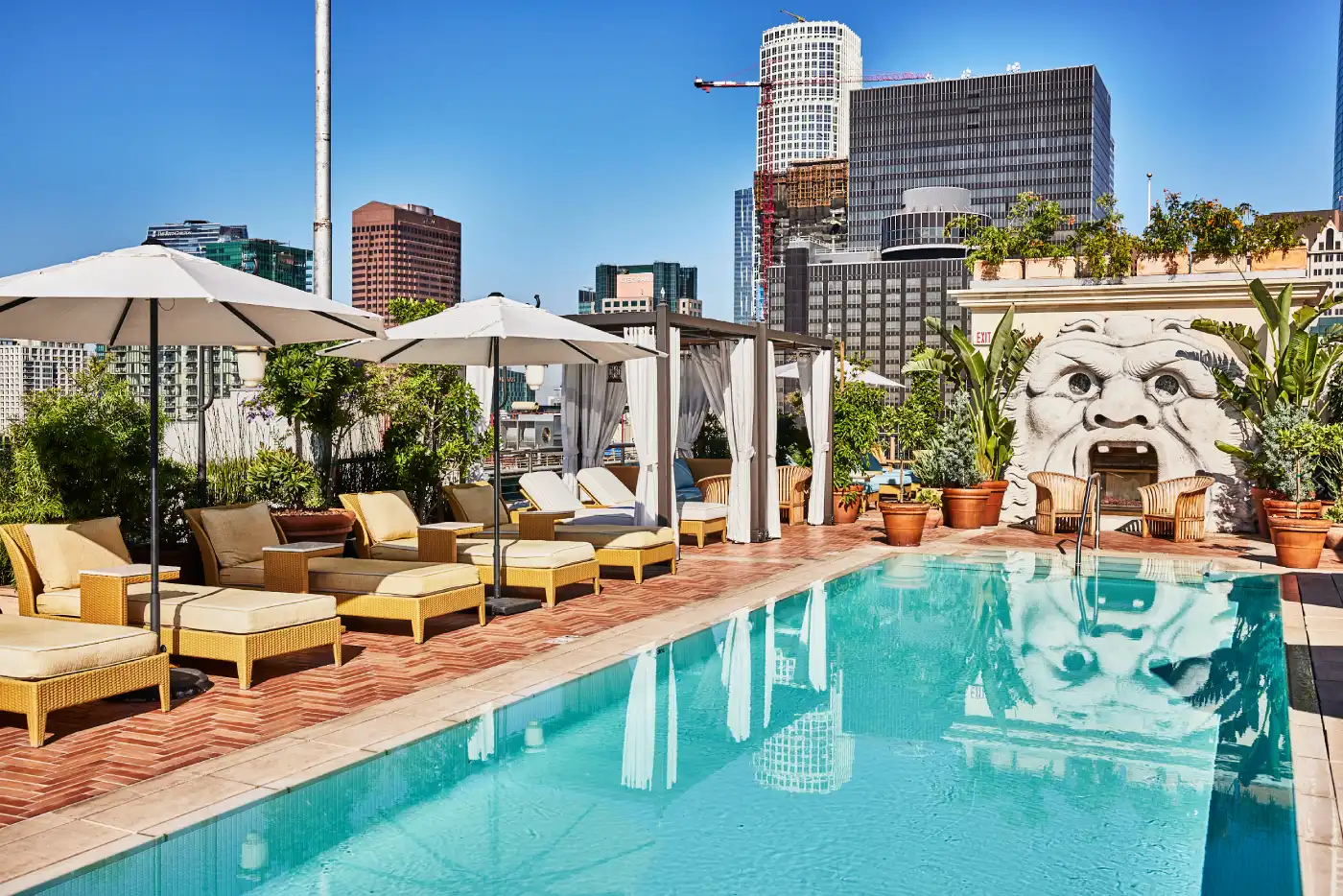 an outdoor pool with lounge chairs and umbrellas