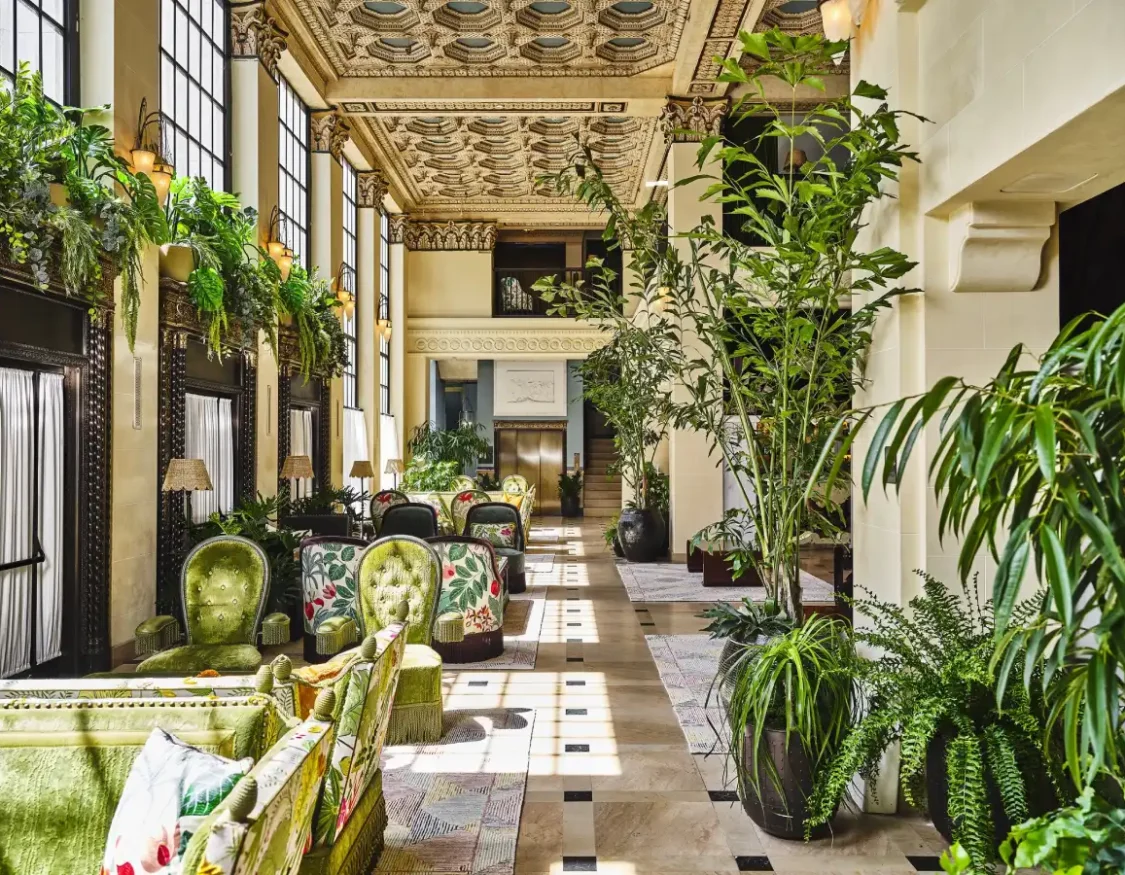 Lush tropical greenery and ornate ceilings frame the plush seating area at Hotel Per La in downtown Los Angeles.