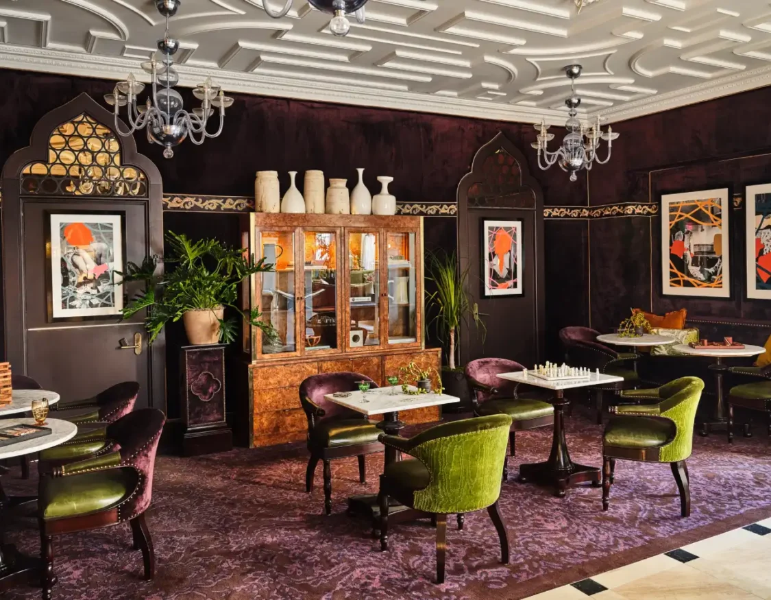 Mustard yellow chairs surround a curved, glowing desk set against artistic curtains in our boutique hotel in LA.