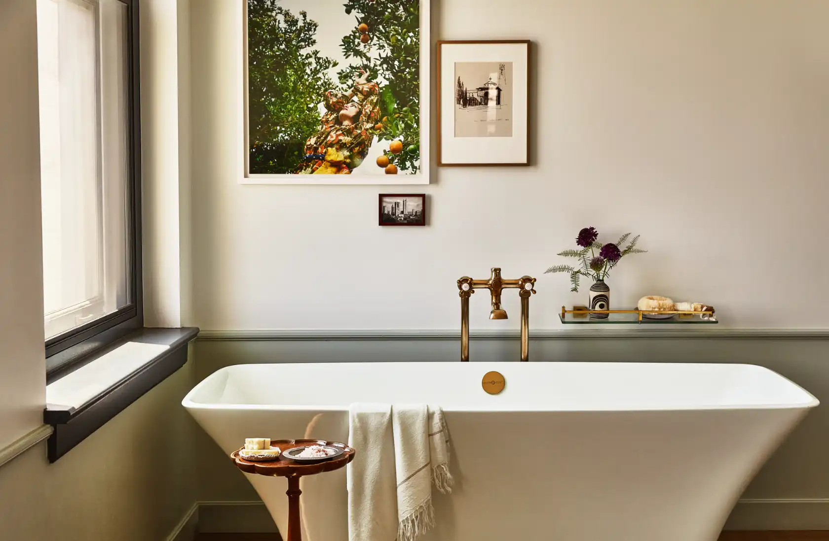 Relax in a white freestanding soaking tub with gold fixtures and curated wall art in a luxury Los Angeles hotel room.