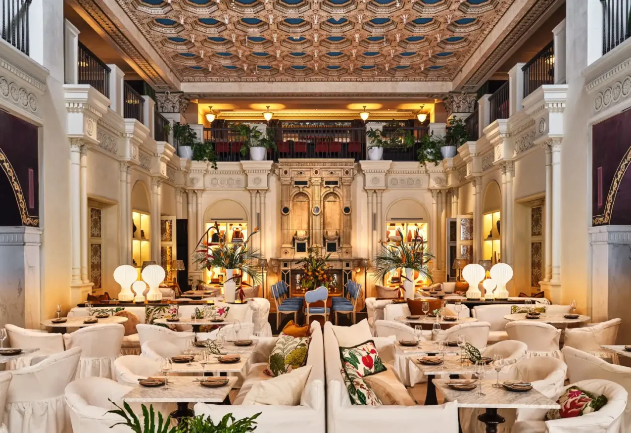 The grand dining room of Ristorante Per L’Ora features an ornate ceiling and plush white seating in downtown LA.
