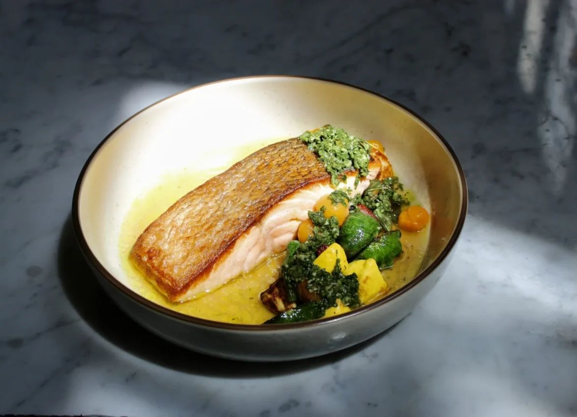 A perfectly seared fish fillet with herb pesto and roasted vegetables served at Ristorante Per L'Ora.