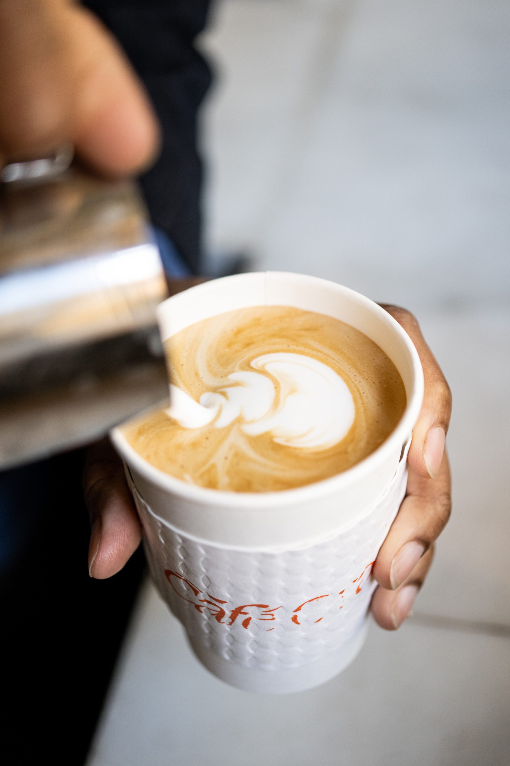 A barista expertly pours steamed milk to create latte art in a takeaway cup at Cafe Ora in downtown Los Angeles.