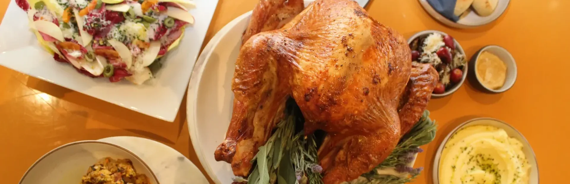 A golden roasted turkey is surrounded by gourmet sides for a festive meal at Ristorante Per L'Ora.