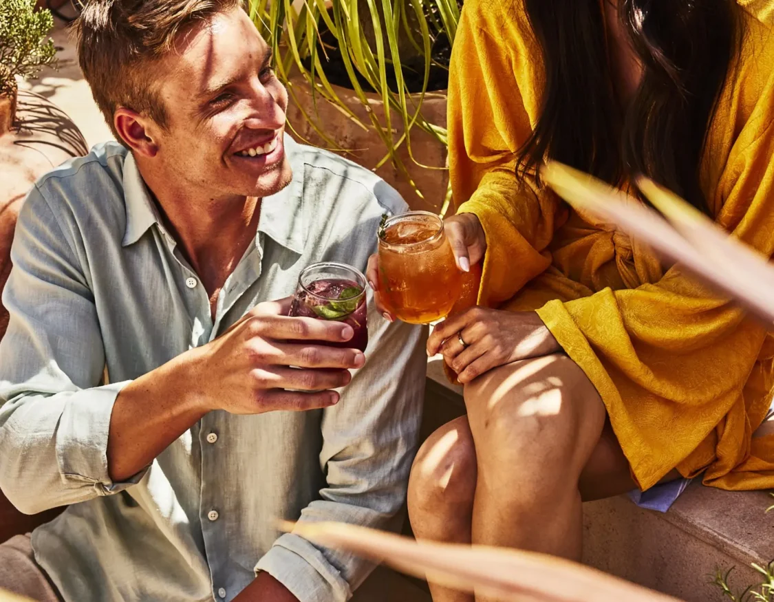 A couple toasts with craft cocktails while relaxing on the sun-drenched patio of Bar Clara in downtown Los Angeles.