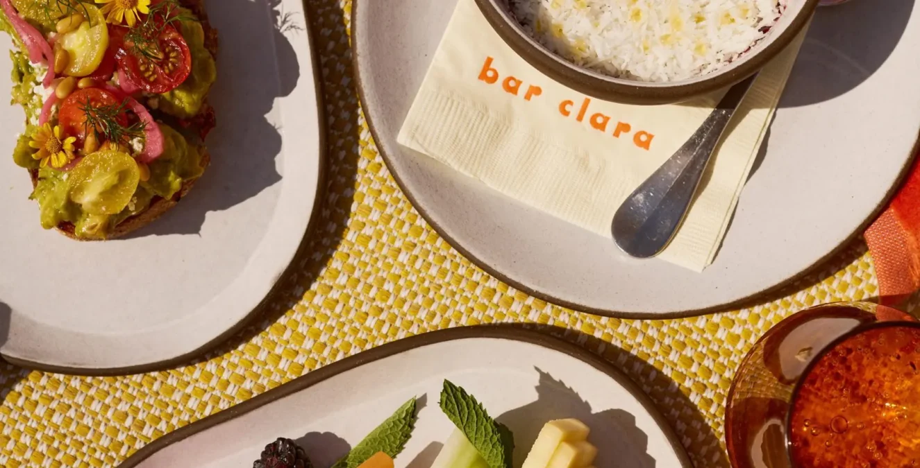 A vibrant poolside spread of fruit and avocado toast at Bar Clara, part of our rooftop pool hotel in Los Angeles.