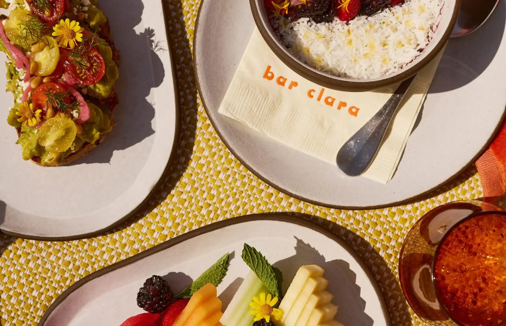 A vibrant poolside spread of fruit and avocado toast at Bar Clara, part of our rooftop pool hotel in Los Angeles.