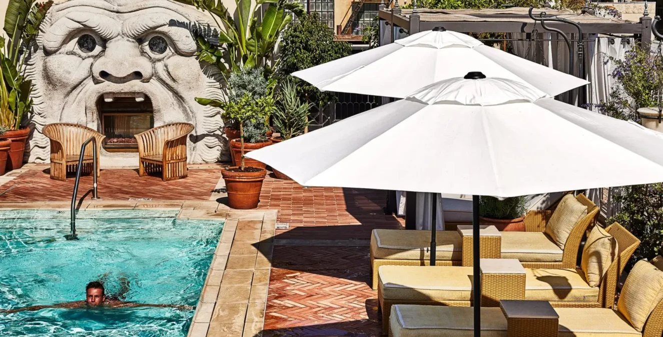 A swimmer enjoys the rooftop pool at Bar Clara, surrounded by loungers and city views in downtown Los Angeles.