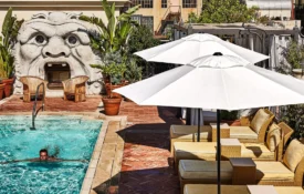 A swimmer enjoys the rooftop pool at Bar Clara, surrounded by loungers and city views in downtown Los Angeles.