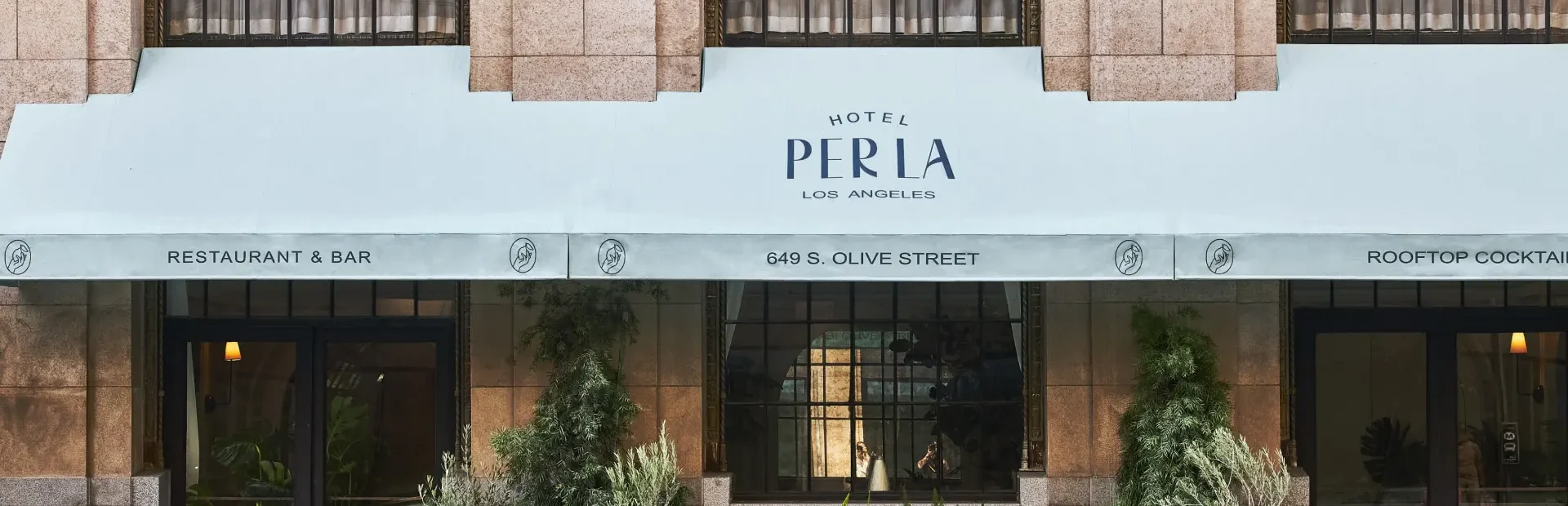 A light blue awning and potted plants mark the entrance to Hotel Per La, one of the top boutique hotels in Los Angeles.