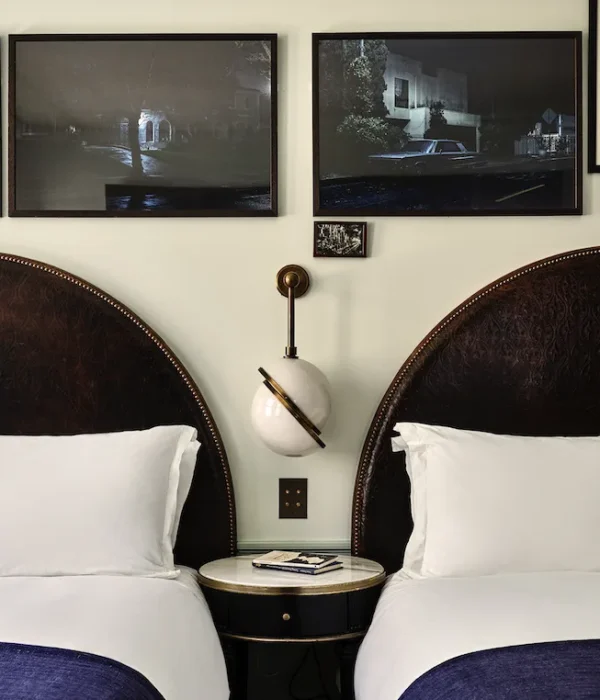 A hotel room with two large beds and a side table between them