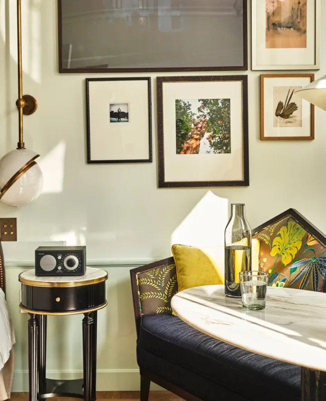 Sunlight streams into a luxury hotel suite in Los Angeles featuring an artistic gallery wall and cozy dining nook.
