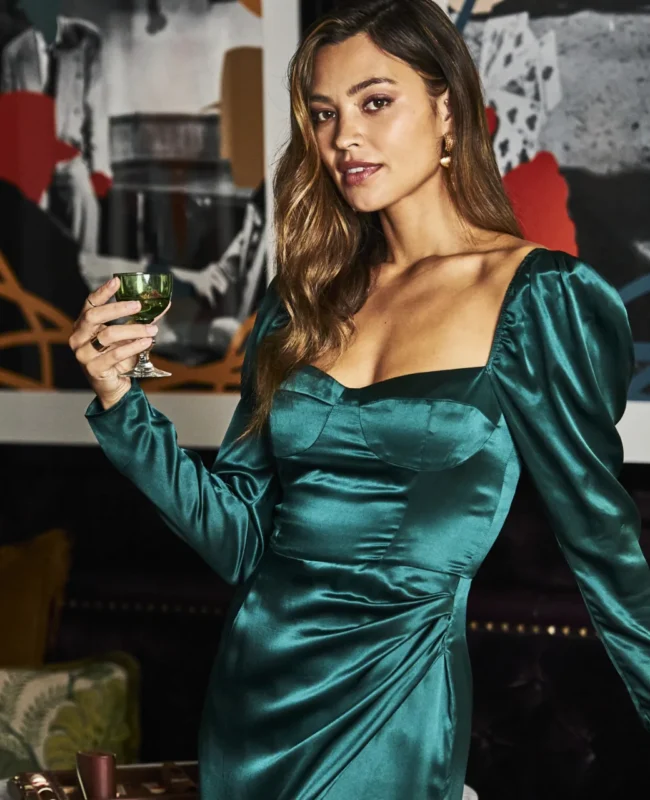 A woman in a green satin dress holds a cocktail in the stylish Bar Clara at our boutique hotel in downtown LA.